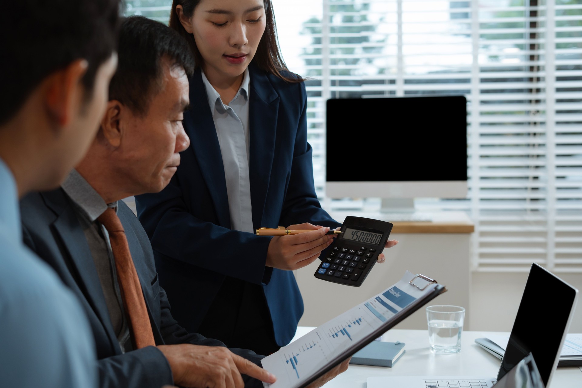 Business consultants discuss tax, merger strategy and restructuring in modern office.